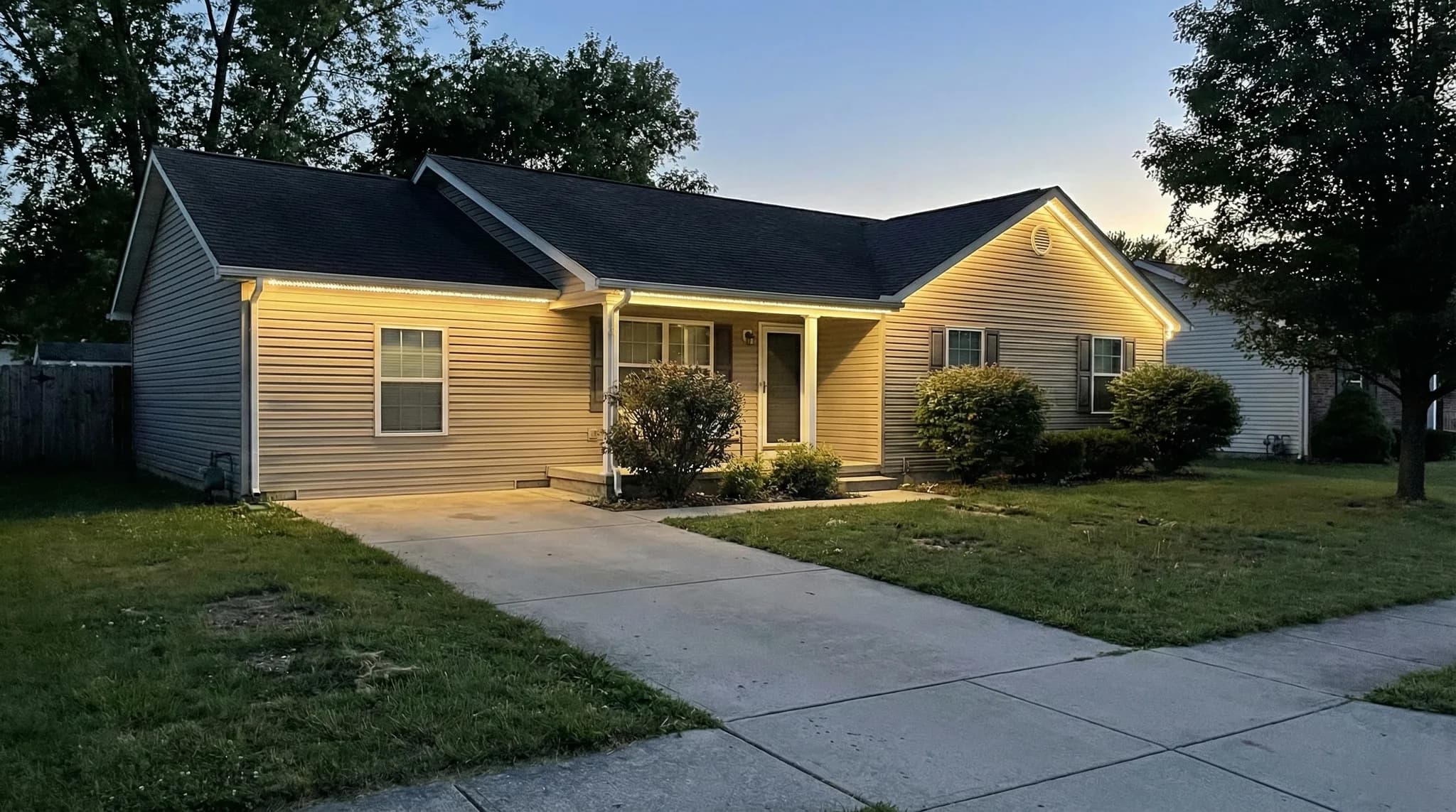 Ranch home with warm downlighting on front porch and entry